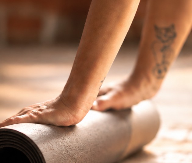 Mains qui déroulent un tapis de yoga
